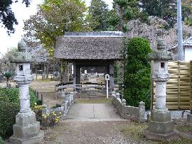 六地蔵寺：参道に設けられた茅葺屋根の山門と石燈篭